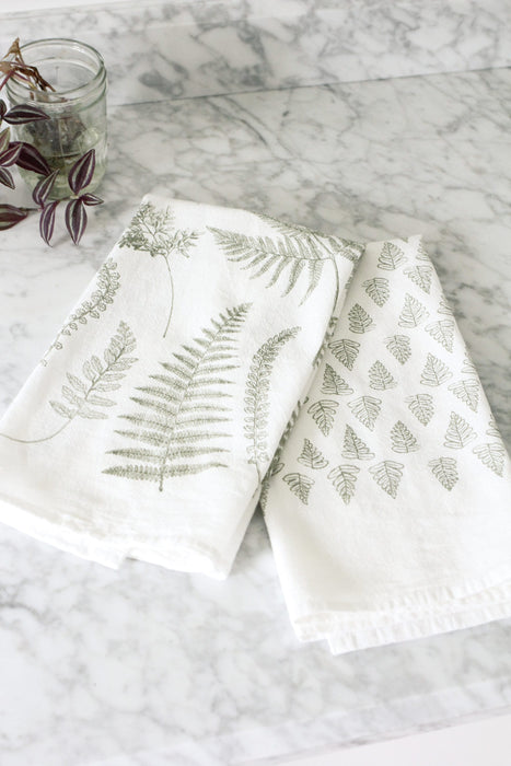 Fern Fronds Tea Towel Set of 2 for the kitchen. One white flour sack tea towel is covered by a variety of large sage green fern fronds and the other white towel is covered by a pattern of small repeating sage green fern leaves.
